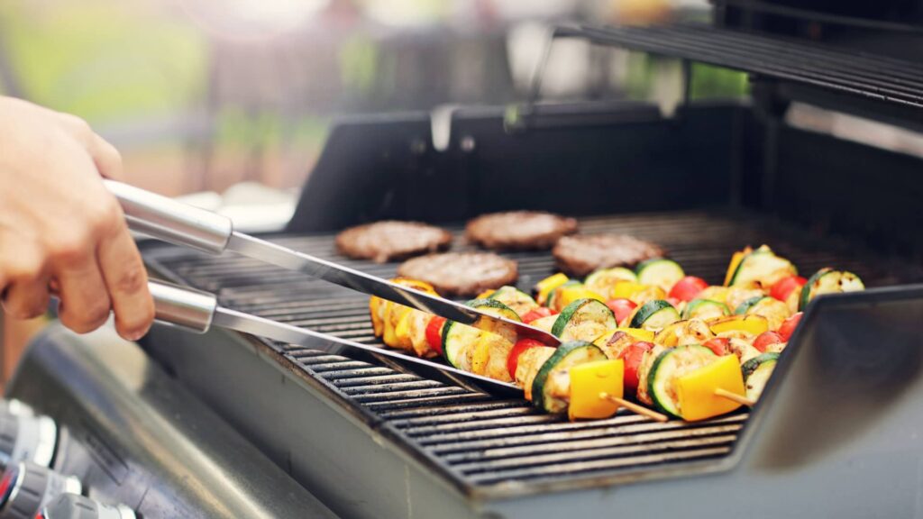 Closeup of Person Grilling Kebobs and Burgers min